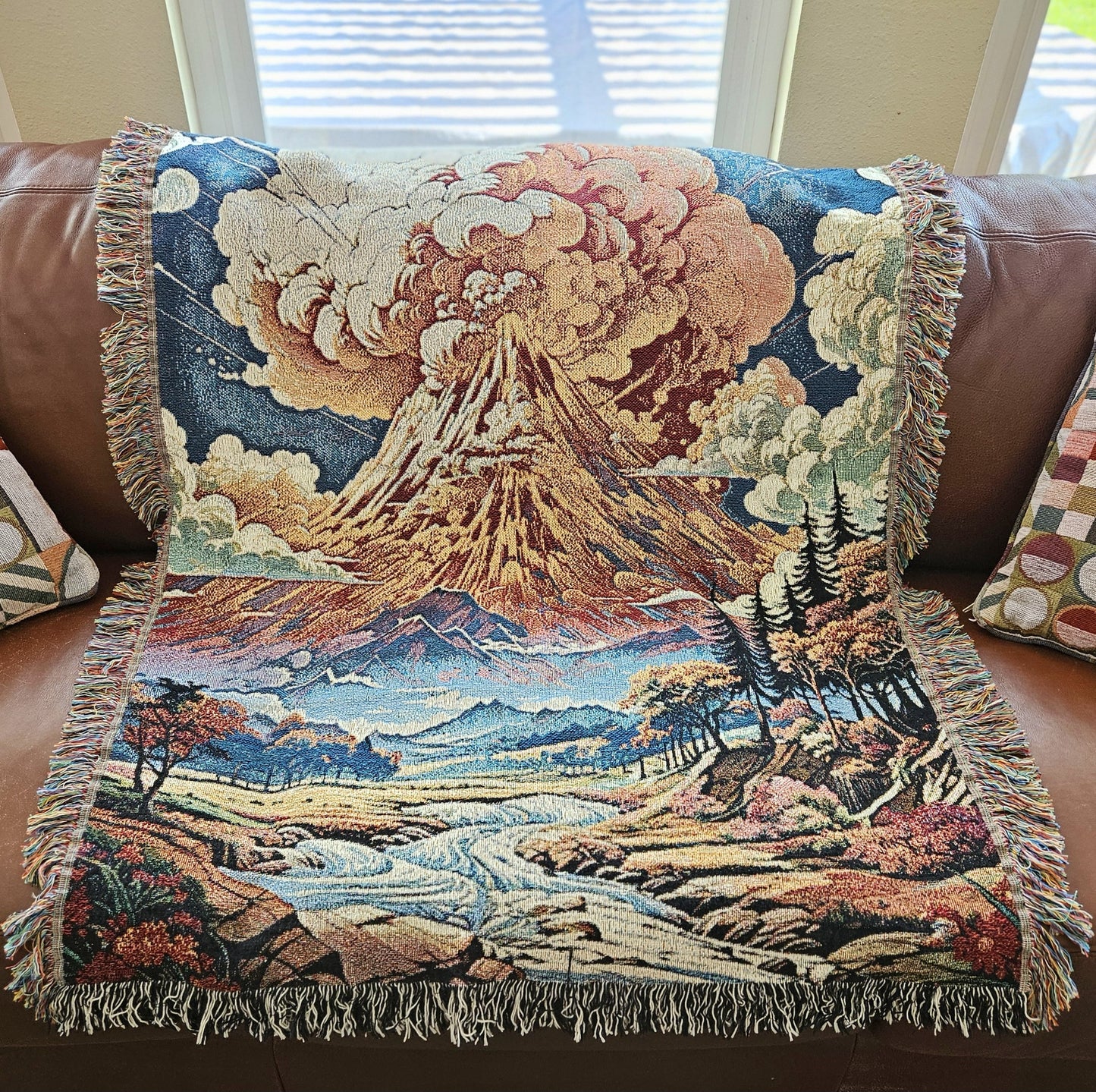 Summit Eruption Woven Blanket featuring a vibrant tapestry of a volcano, crafted from 100% cotton, perfect as a decorative throw or wall art.