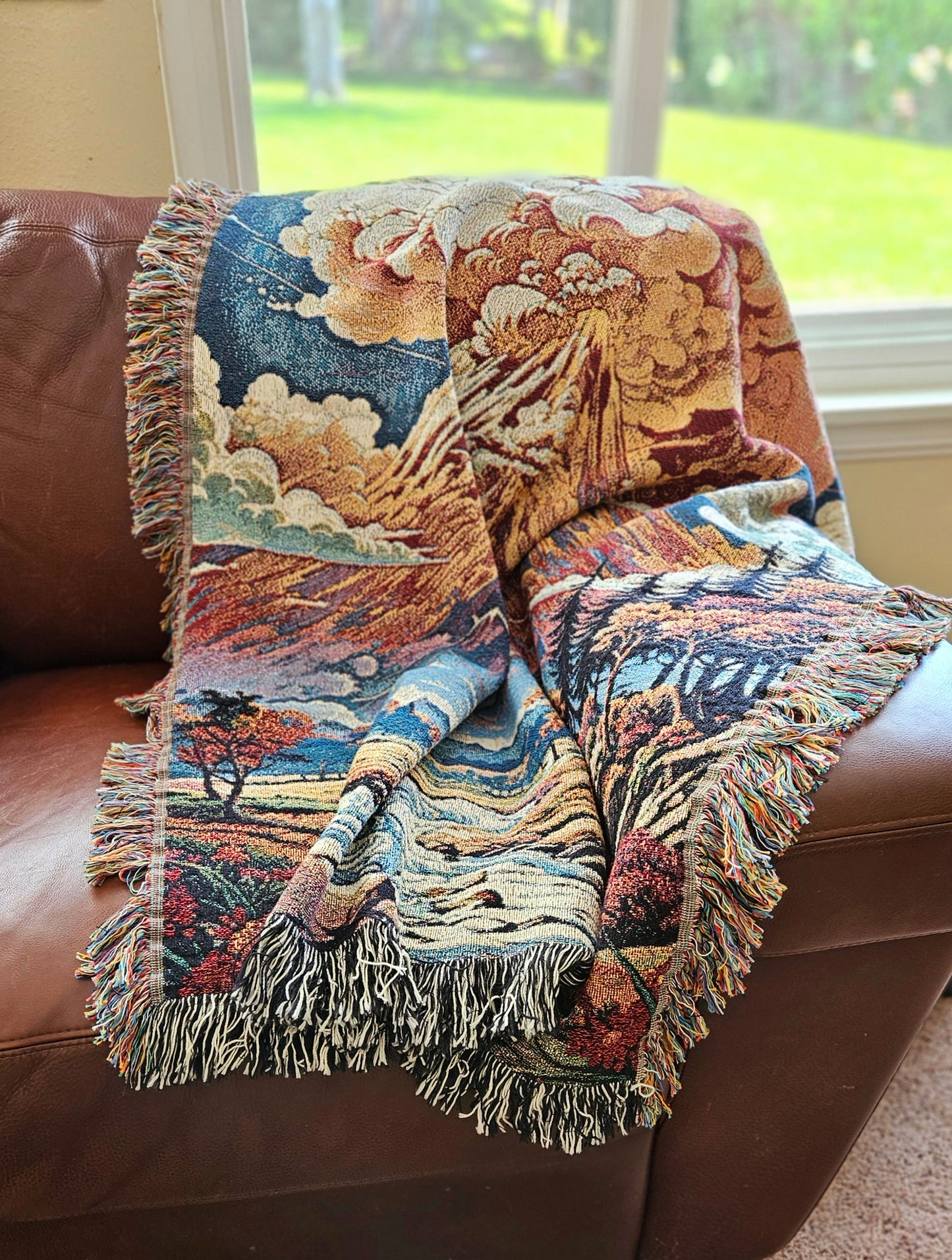 Summit Eruption Woven Blanket featuring a vibrant tapestry of a volcano, crafted from 100% cotton, perfect as a decorative throw or wall art.