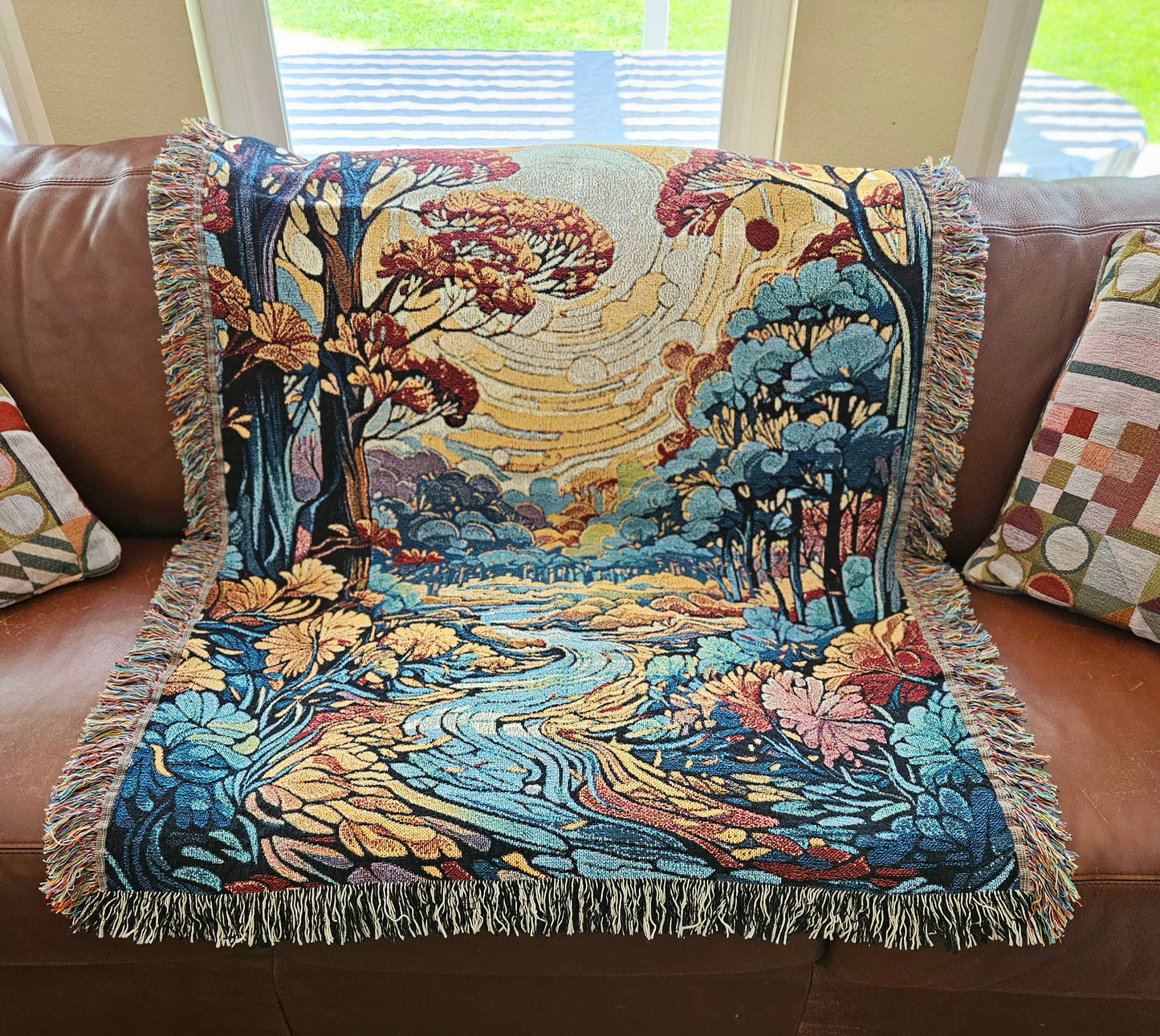 Flowing Serenity Woven Blanket featuring a colorful tapestry of trees and a river, highlighting its luxurious, intricate design.
