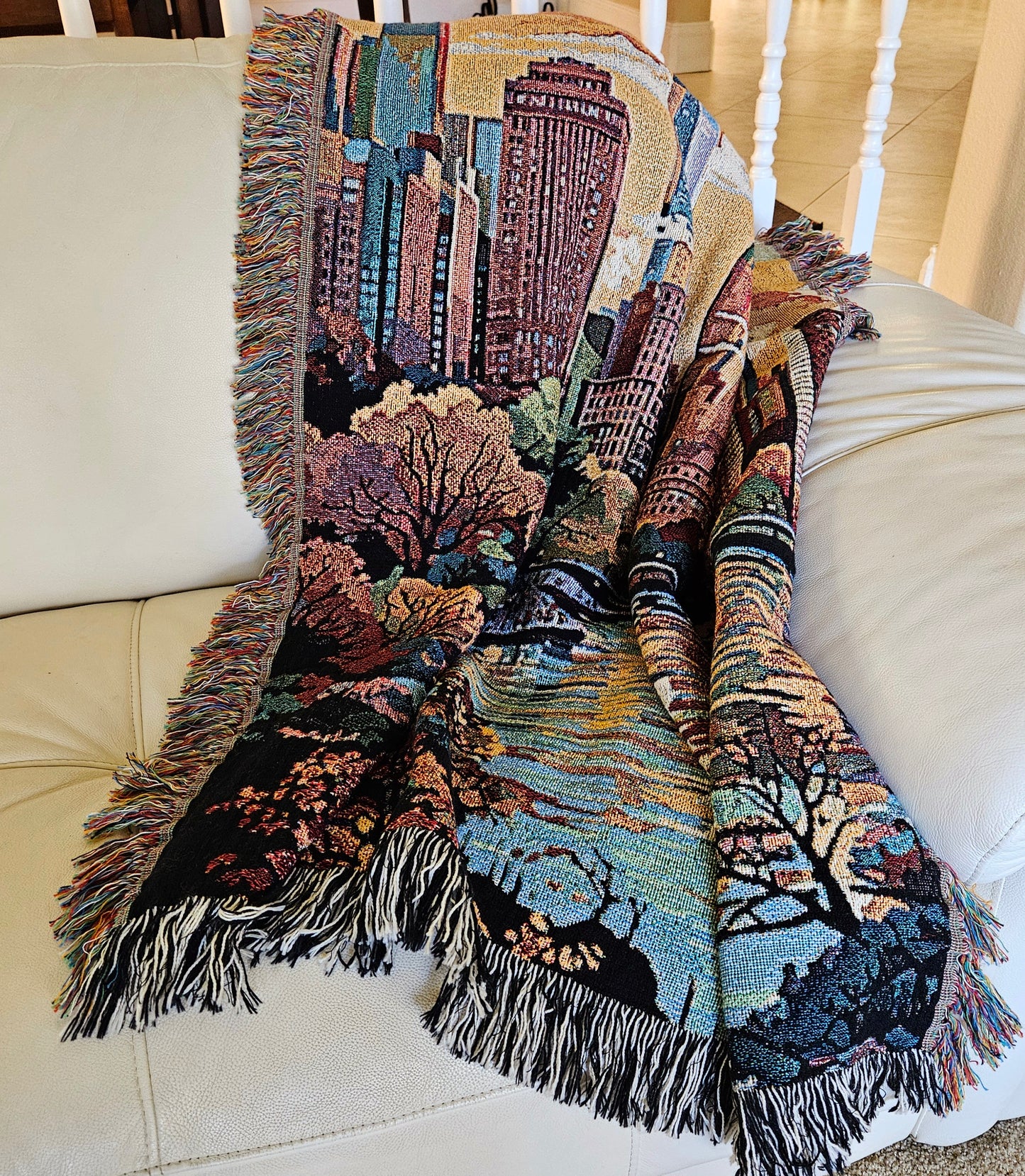 Woven blanket featuring a colorful tapestry of a city skyline and lake, titled New York in Pastels I, made from 100% pure cotton.