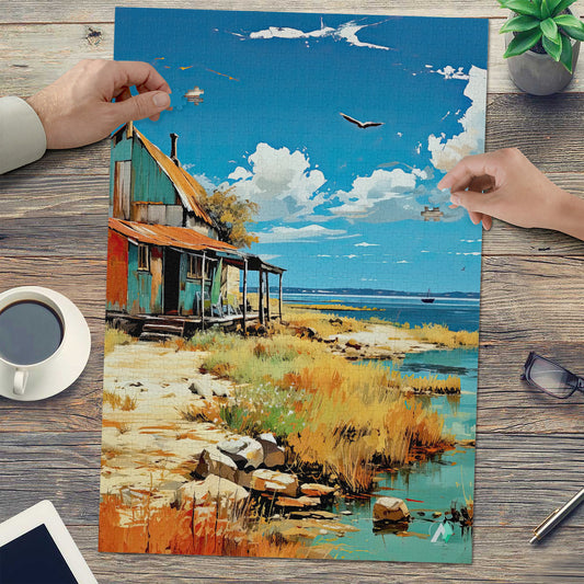 OlΓ©ron Shanty Puzzle depicts a house by the sea with clouds, crafted from premium ivory cardboard, available in 500 and 1000 pieces.