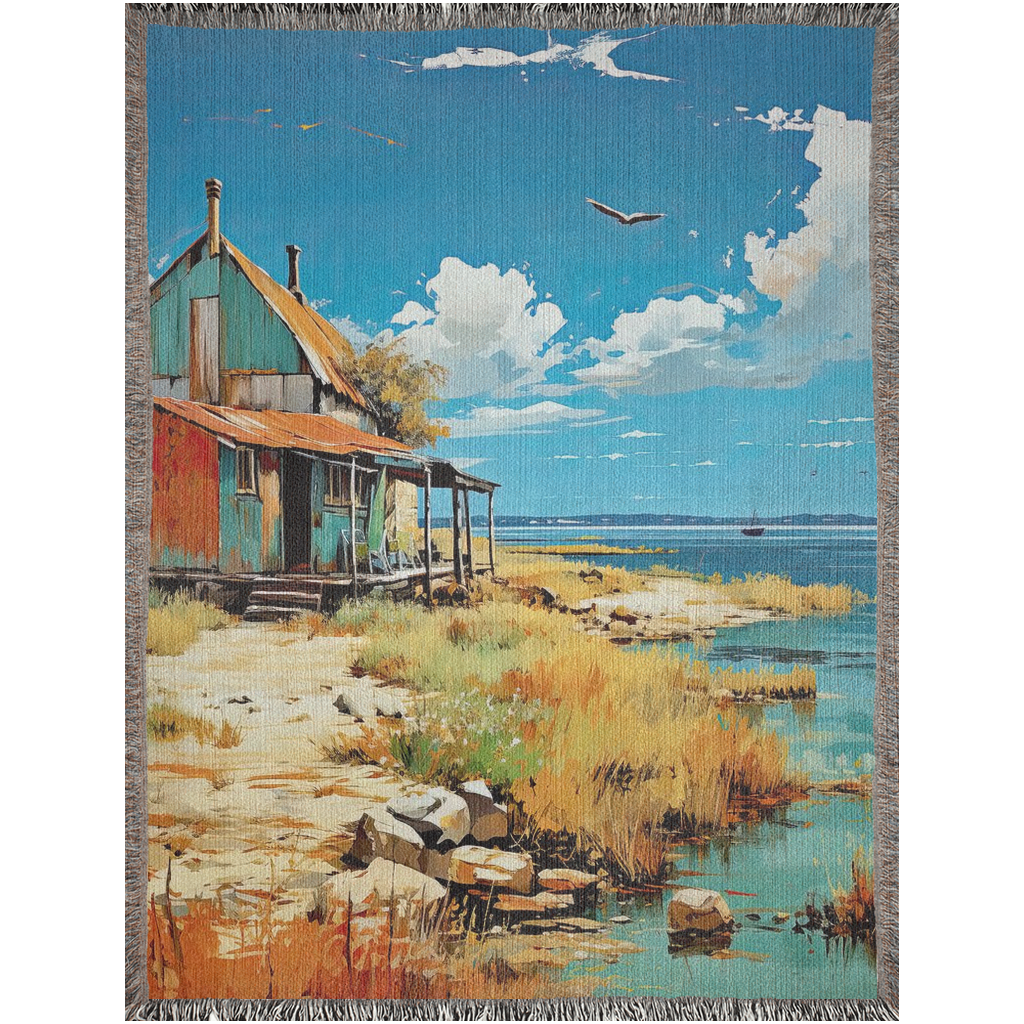 Oléron Shanty Woven Blanket featuring a house by the shore, showcasing intricate craftsmanship and made from 100% pure cotton for home décor.